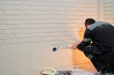 Master lays tiles on the wall. Builder installs tiles for renovation work, wall decor sticker in apartment